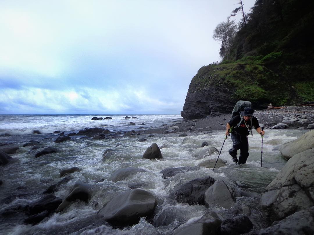 Man crossing a beach river outlet on the Lost Coast